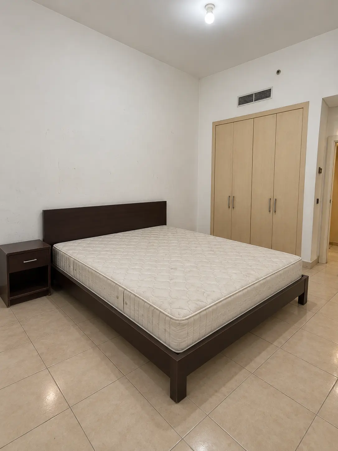Reconstructed basic bedroom before renovation with old furniture and an uncovered bed
