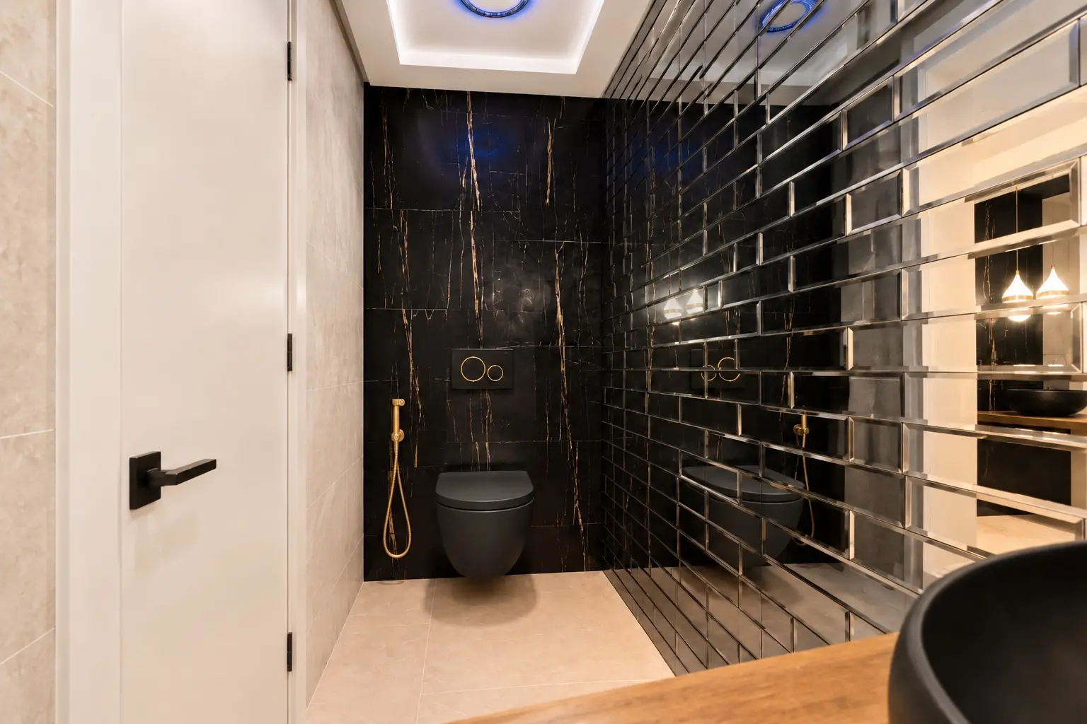 Renovated guest toilet with black stone, mirrored wall and gold fittings